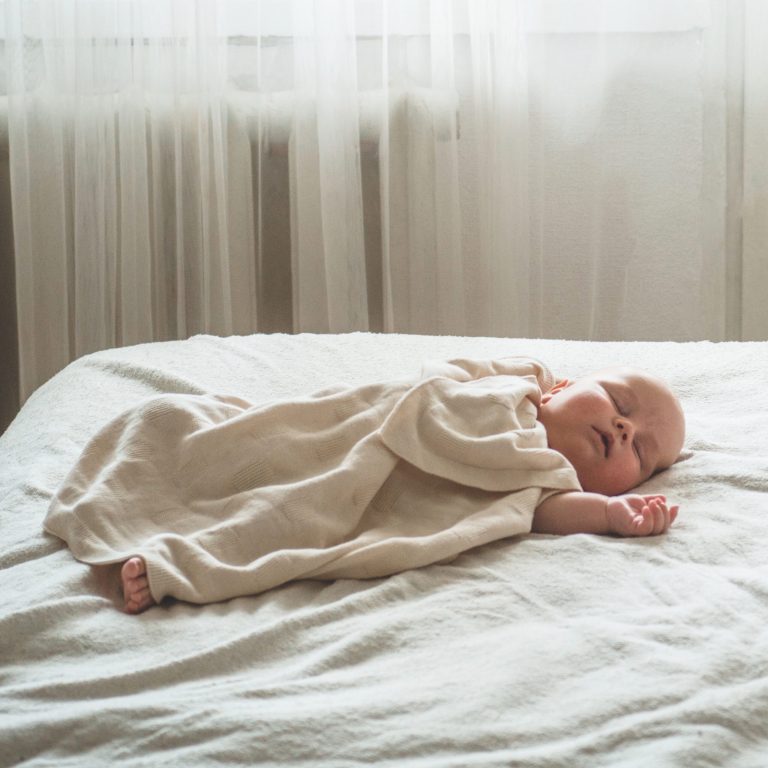 Home portrait of a newborn baby on the bed. The child is sleeping.